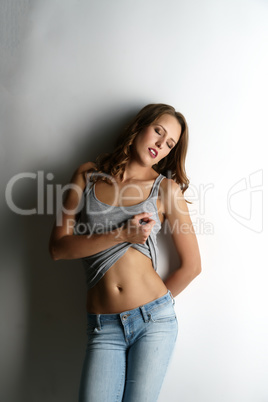 Sensual young woman posing leaning against wall