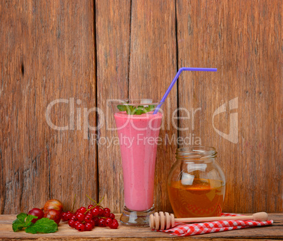 berry smoothie, currants, gooseberries and honey on a wooden sur