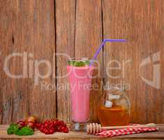 berry smoothie, currants, gooseberries and honey on a wooden sur