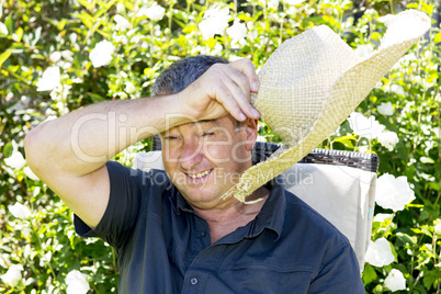 Man with straw hat sitting in garden chair