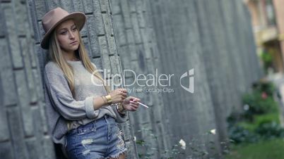 Woman smoking and leaning on the loft brick wall