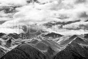 Black and white view on snowy mountains and cloudy sky at evenin