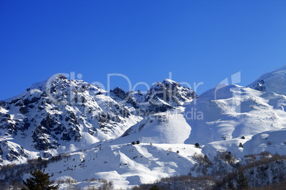 Snowy mountains and off-piste slope on sunny day