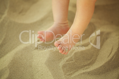 Newborn baby feet playing in the sand