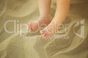 Newborn baby feet playing in the sand