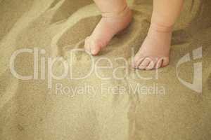 Newborn baby feet playing in the sand