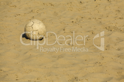 Ruined soccer ball on beach sand