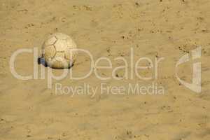 Ruined soccer ball on beach sand