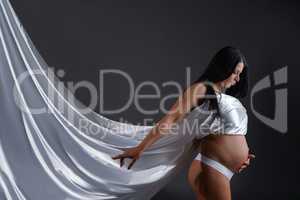 Photo of gorgeous pregnant woman posing with silk