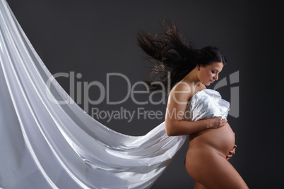 Naked pregnant woman posing with flying cloth