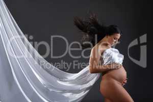 Naked pregnant woman posing with flying cloth