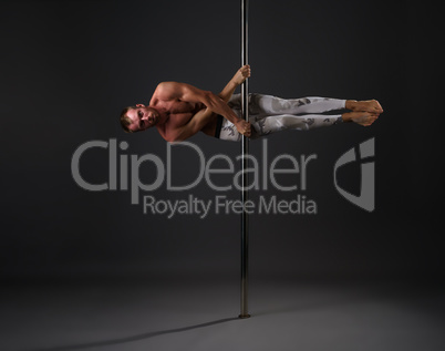 Studio image of male dancer exercising on pole