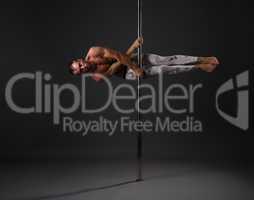 Studio image of male dancer exercising on pole