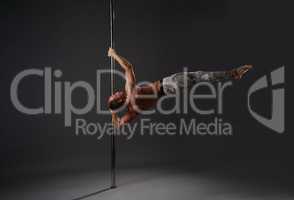 Strong gymnast exercising on pylon in studio