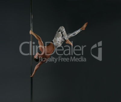 Male athlete doing acrobatic trick on pylon