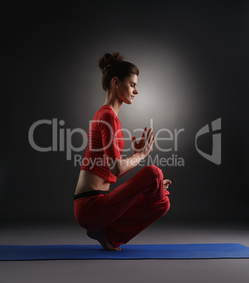 Yoga in studio. Girl doing asana, on gray backdrop
