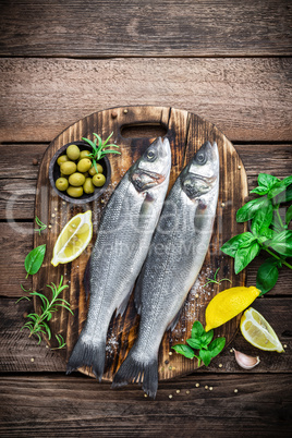 raw seabass fish on wooden background top view