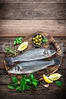 raw seabass fish on wooden background top view