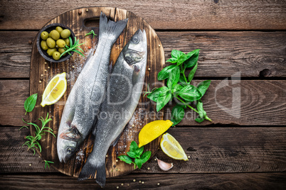 raw seabass fish on wooden background top view