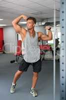 At gym. Handsome athlete posing showing his biceps