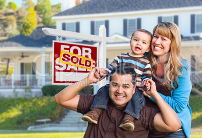 Young Family in Front of Sold Real Estate Sign and House