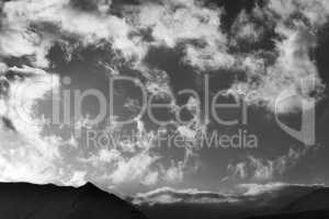 Black and white sky with clouds and mountains in evening