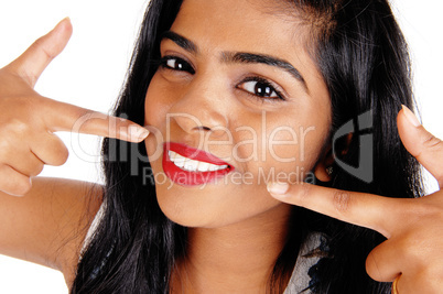 Woman pointing at her white teeth.
