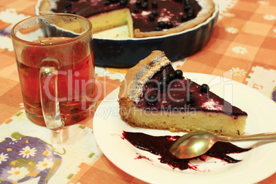 piece of pie with bilberry on the plate and cup of tea