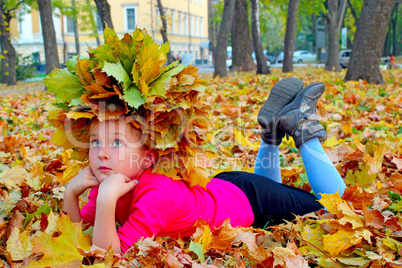 girl with a wreath of yellow leaves lying on the leaves
