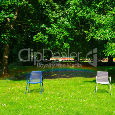 Summer park, green lawn, garden chairs and an automatic watering