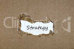 The word strategy appearing behind torn paper