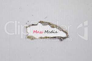 The word mass media appearing behind torn paper