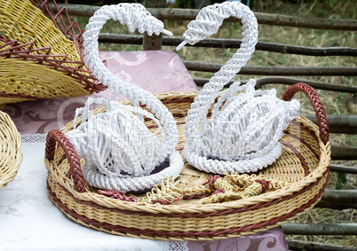 Decorative figurines of swans on a wicker platter.
