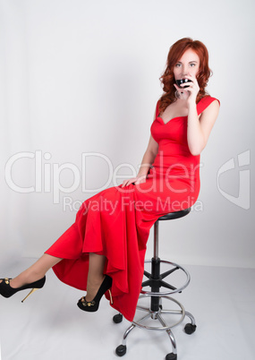 portrait Elegant young redhead woman in red dress, having a glass of wine