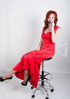 portrait Elegant young redhead woman in red dress, having a glass of wine