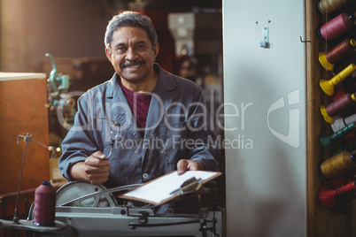 Portrait of smiling shoemaker holding clipboard and spectacle