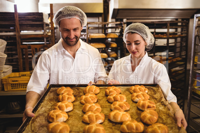 Female and male baker holding a tray of michetta