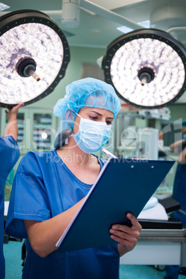 Female surgeon writing on clipboard in operation room