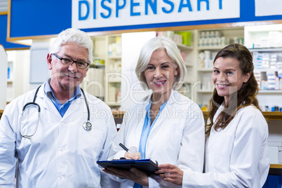 Pharmacists writing on clipboard in pharmacy