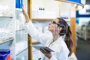 Pharmacist holding digital tablet while checking medicine