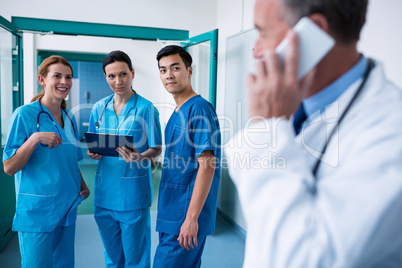Smiling surgeons standing together with clipboard in corridor