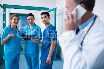 Smiling surgeons standing together with clipboard in corridor Smiling surgeons standing together with clipboard in corridor