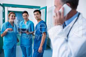 Smiling surgeons standing together with clipboard in corridor