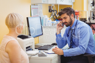 Doctor sitting at his desk and talking on phone