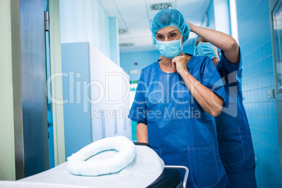 Nurse helping a surgeon in tying surgical mask
