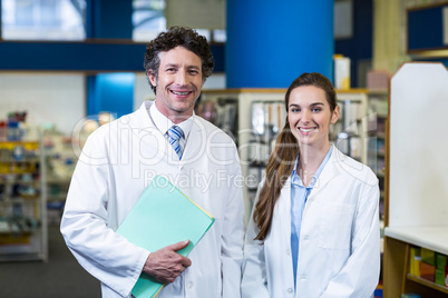 Smiling pharmacists standing with file in pharmacy