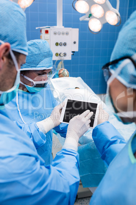 Surgeons using digital tablet and patient lying on operation bed