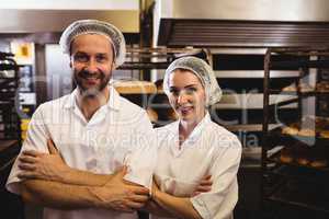 Portrait of female and male baker standing with arms crossed