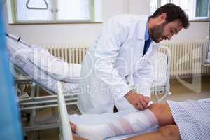 Doctor bandaging leg of patient