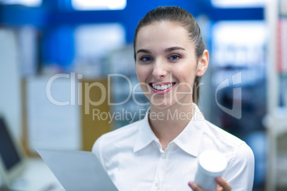 Pharmacist holding prescription while checking medicine in pharm